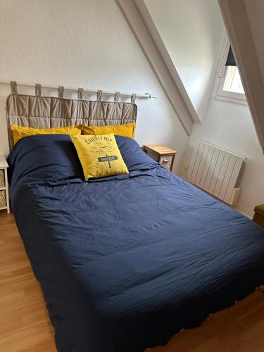 - un lit avec une couette bleue et un oreiller jaune dans l'établissement Charmante maison avec piscine , plage à 500 m , location du samedi au samedi !!!, à Erdeven