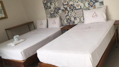 2 letti in una camera con lenzuola e cuscini bianchi di Hotel Montana a Villahermosa