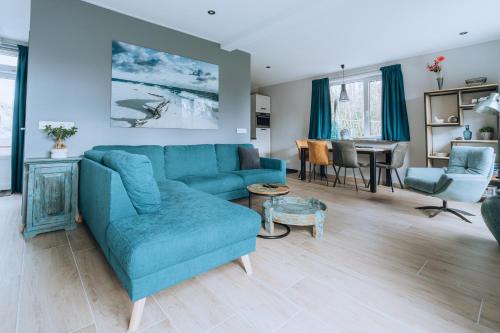 a living room with a blue couch and a table at Strand Thema Vakantiewoning bij B&B Gezond aan Zee - Toegang Wellnesstuin meerprijs in Ouddorp