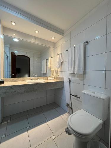 a bathroom with a toilet and a sink and a mirror at Flat no Gonzaga - Santos in Santos