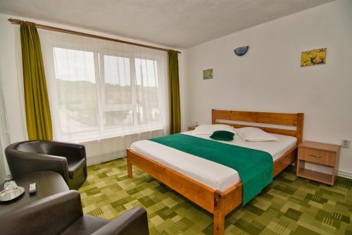 a bedroom with a bed and a chair and a window at Casa Sima in Călimăneşti