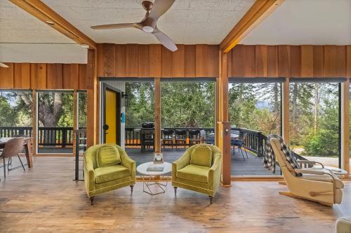 a living room with chairs and a porch with a deck at Honea Bee Hideout in Bass Lake Annex