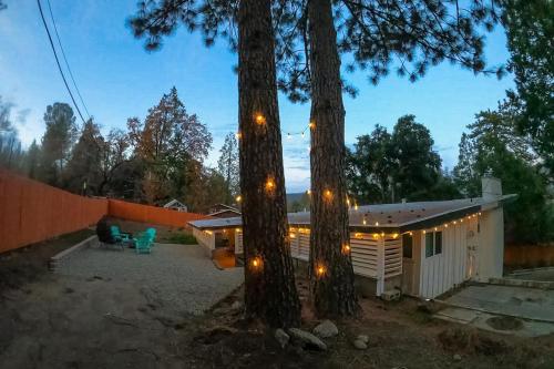 a small cabin with lights between two trees at Honea Bee Hideout in Bass Lake Annex