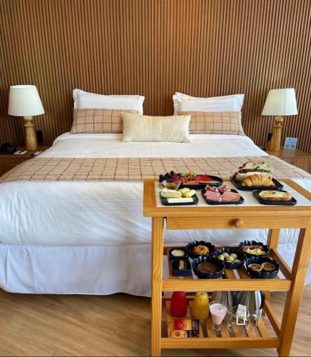 a bed with a tray of food on a table at Hotel Espadarte in Iriri