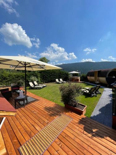 a wooden deck with an umbrella and some chairs at Folgaria Post Hotel in Folgaria