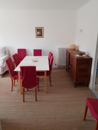 une salle à manger avec une table blanche et des chaises rouges dans l'établissement Spacious House With Garden In Downtown, à Six-Fours-les-Plages