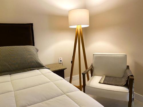 a bedroom with a bed and a chair and a lamp at Rodeio Hotel in Rodeio Bonito