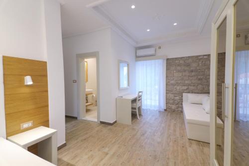 a living room with a white couch and a stone wall at Hotel RR in Herceg-Novi