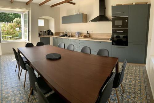 une cuisine avec une grande table et des chaises en bois dans l'établissement Maison de caractère 12 couchages - 300m de la plage de sable Location a la semaine en ete, à Binic