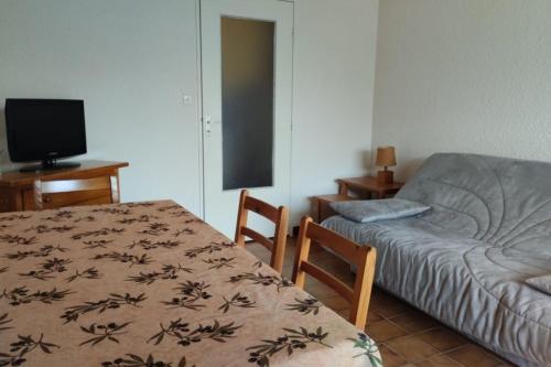 Cette chambre comprend une table, un lit et une télévision. dans l'établissement Pleasant studio near the sea, à Cavalaire-sur-Mer