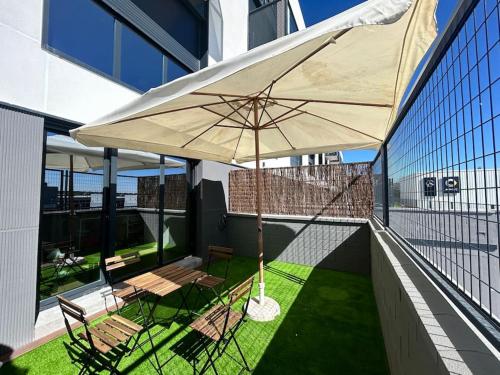 a patio with chairs and an umbrella on a balcony at Loft 007 con jardin, piscina, garaje y Netflix in San Sebastián de los Reyes