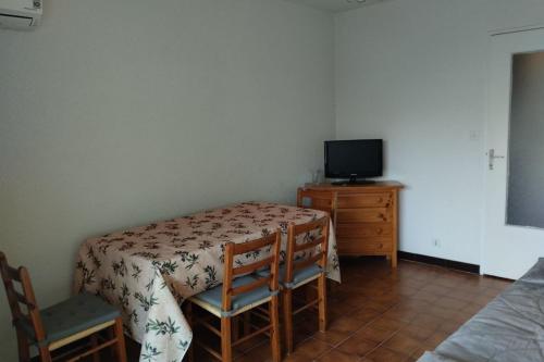 Cette chambre dispose d'une table avec deux chaises et d'une télévision. dans l'établissement Pleasant studio near the sea, à Cavalaire-sur-Mer