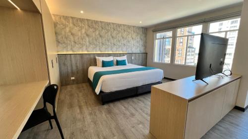 a bedroom with a bed and a desk and a television at Hotel Grand Park in Bogotá