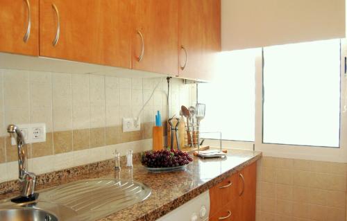 un bancone della cucina con lavandino e cesto di frutta di Apartamentos Atlántico a Punta Umbría