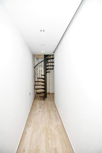 a hallway with white walls and a spiral staircase at Panoramic View over Shkodra's Lake - Serena Home in Shkodër