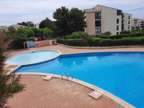 2 grandes piscines en face d'un bâtiment dans l'établissement DOMAINE et MER, à Six-Fours-les-Plages