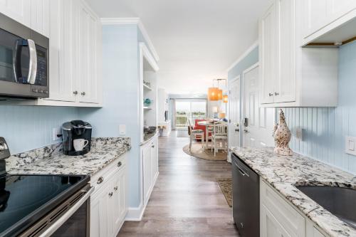 a kitchen with white cabinets and marble counter tops at Sands III #1C - Toes In the Water in Carolina Beach