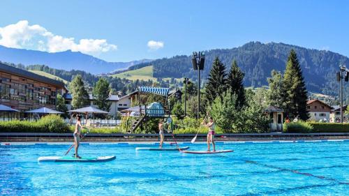 trois filles sont sur des planches à pagaie dans l'eau dans l'établissement Chalet de Denis luxe alpin et emplacement ideal à Megeve, à Megève