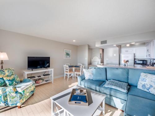 a living room with a blue couch and a kitchen at Sea Colony 21B in Carolina Beach