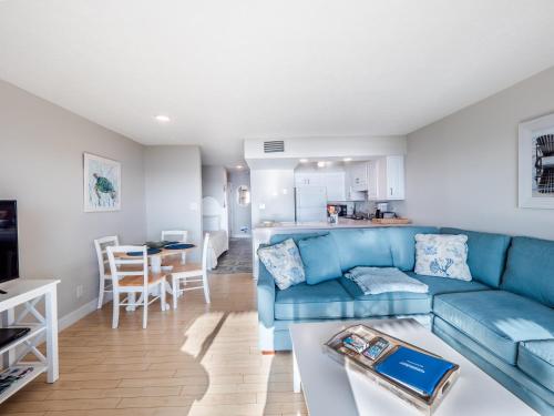 a living room with a blue couch and a kitchen at Sea Colony 21B in Carolina Beach