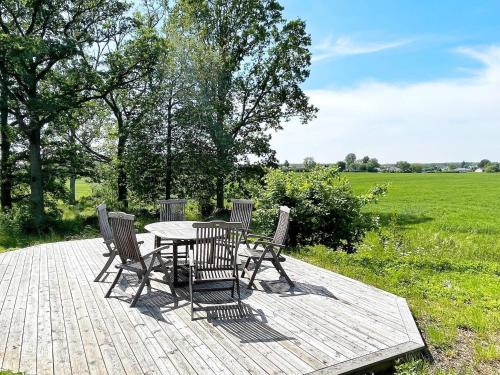 a table and chairs on a wooden deck with a field at 8 person holiday home in HÖGSBY in Högsby