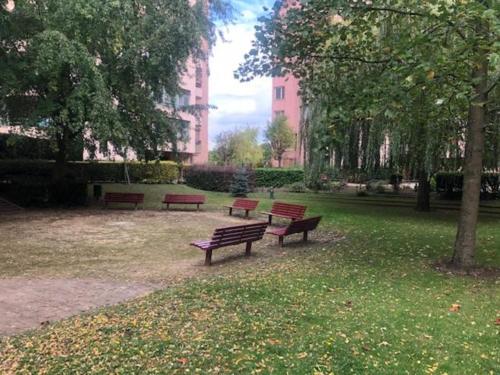 trois bancs dans un parc avec des arbres et un bâtiment dans l'établissement Appartement avec grand salon, barbecue et terrasse proche Paris et Disney, à Champs-sur-Marne