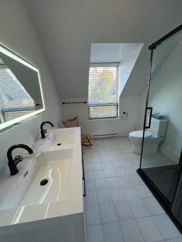 a white bathroom with a sink and a toilet at Maison du Havre Grand Duplex in La Malbaie