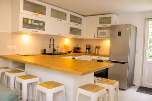 a kitchen with a counter and a refrigerator and stools at Ty Dany-wifi-plage à pieds in Crozon