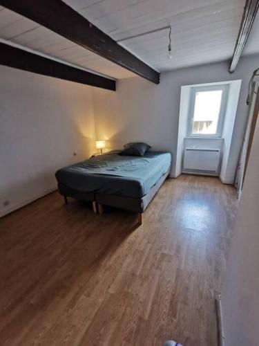 - une chambre avec un lit dans une pièce dotée de parquet dans l'établissement Confortable et Fonctionnelle, à Cléder