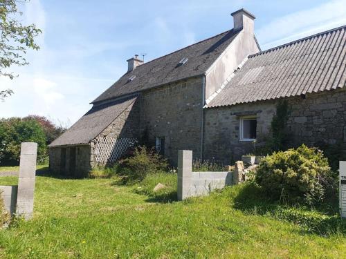 un vieux bâtiment en pierre dans un champ à côté d'un cimetière dans l'établissement Confortable et Fonctionnelle, à Cléder