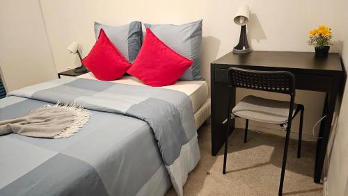 - une chambre avec un bureau et un lit avec des oreillers rouges dans l'établissement Nice business apartment Paris, à Nanterre