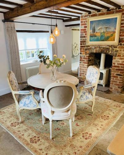 a dining room with a table and chairs and a fireplace at Beautiful 18th century cottage in Arundel in Arundel