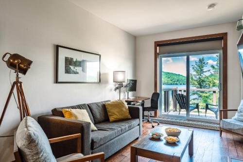 a living room with a couch and a table at Lakefront Mountain View Remote Work - 1 Bd Suite in Lac-Superieur
