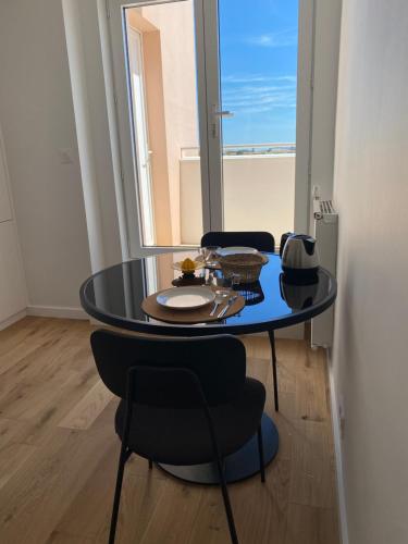 une table et des chaises dans une pièce avec une fenêtre dans l'établissement Appartement terrasse centre ville, à La Rochelle