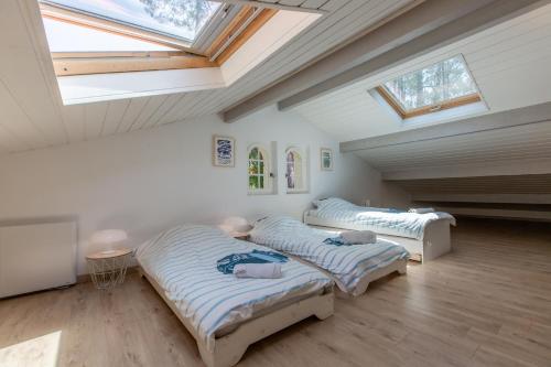 Cette chambre mansardée comprend 3 lits et une lucarne. dans l'établissement Maison Landaise familiale 10 pers au cœur de la forêt, à Seignosse