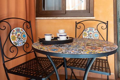 a table with two chairs and a table with cups on it at Tri Re e 'na Regina in Cinisi