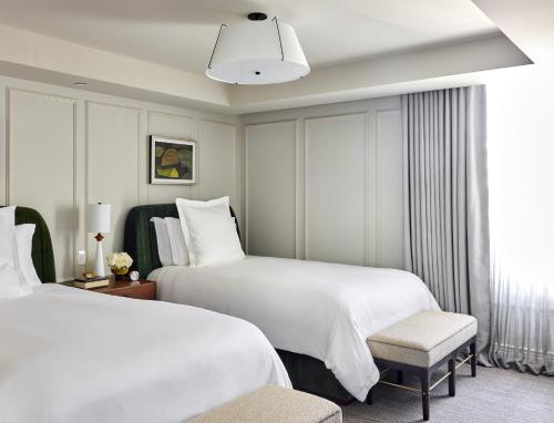 a hotel room with two beds and a chair at Rosewood Hotel Georgia in Vancouver