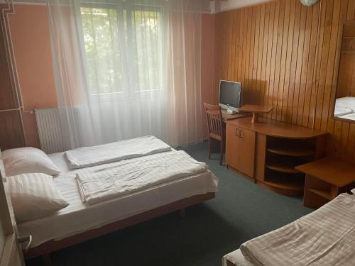 a bedroom with two beds and a desk with a computer at Tifani Szálló in Balatonlelle