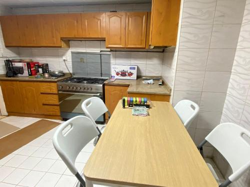a kitchen with a wooden table and white chairs at Luxury Private Rooms for Men in Sharjah