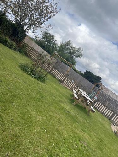 a wooden bench sitting in a field next to a fence at The Crown Inn in Gayton
