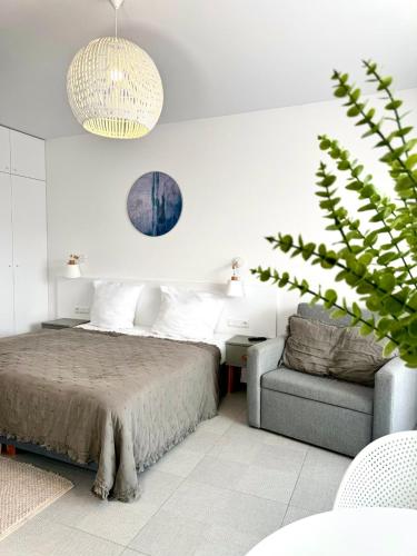 a bedroom with a bed and a chair and a plant at Aquamarina Prima Gold in Międzyzdroje