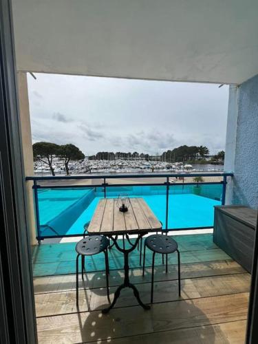 - une table sur un balcon avec vue sur la piscine dans l'établissement Charmant studio rénové, à Hourtin