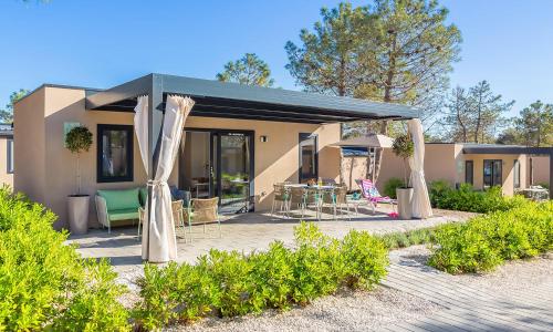 a house with a patio with a table and chairs at Aminess Style Glamping Villas & Holiday Homes Avalona in Povljana