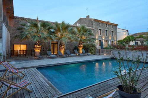 une piscine bordée de palmiers et de chaises ainsi qu'un bâtiment dans l'établissement Domaine du Fresquel, à Pezens