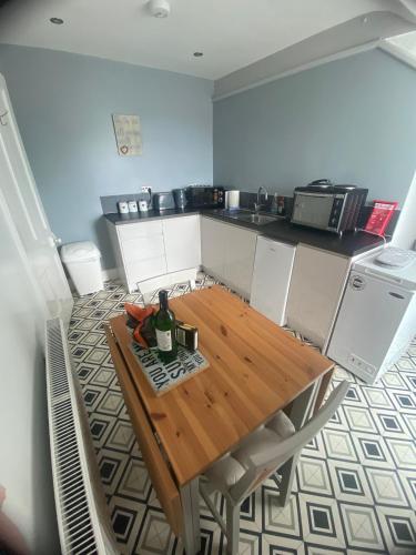 a kitchen with a wooden table with a bottle of wine at Bay View Apartment in Newbiggin-by-the-Sea