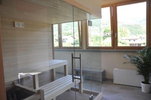 a sauna with a bench and a glass wall at Tullio Hotel in Gravedona