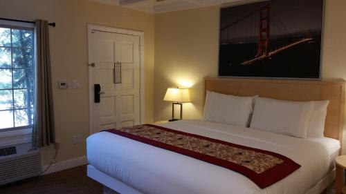 a bedroom with a large white bed and a window at Marin Lodge in San Rafael