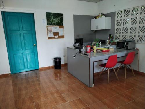 cocina con encimera y 2 sillas rojas en Casa Hostal Bouvá, en El Valle
