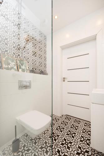 a bathroom with a shower door and a toilet at Manufaktura Residence - Apartamenty Industrial z Parkingiem i Dwoma Łazienkami in Łódź