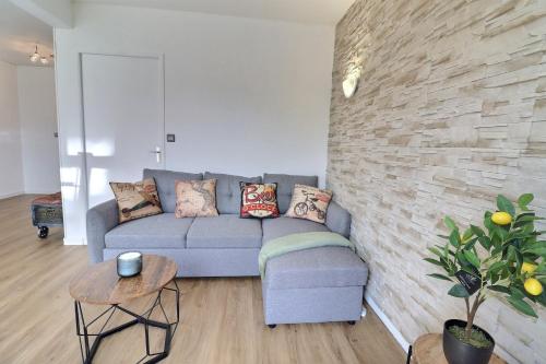 un salon avec un canapé et un mur en pierre dans l'établissement Le Factory - Grand & Lumineux - Mon Groom, à Troyes